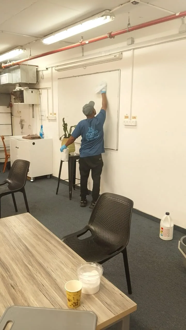 עובד ניקיון של גולד קלין מנקה קיר במשרד