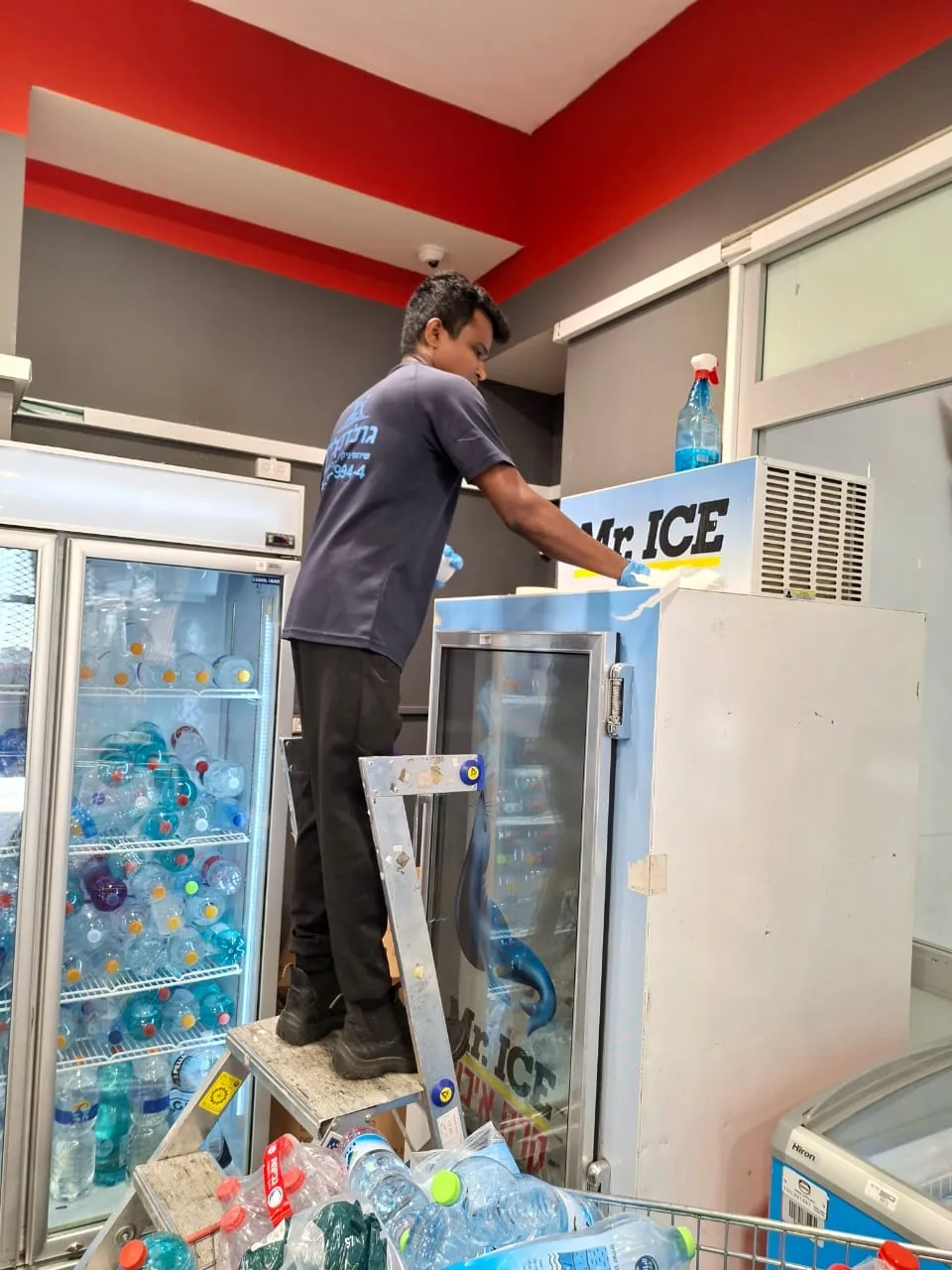 עובד גולד קלין מנקה מקרר משקאות בחנות